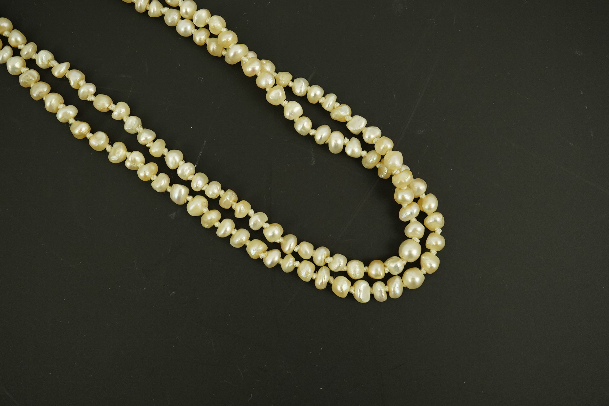 An antique twin strand baroque pearl necklace, with pearl set gold clasp bordered with single chain set with four graduated old mine cut diamonds